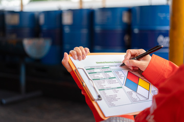A safety officer is checking on the hazardous material checklist form with chemical storage area