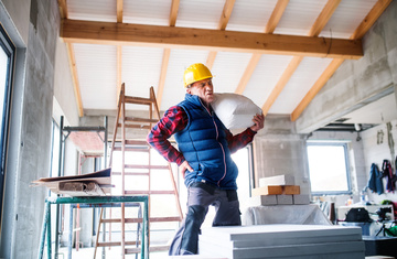 Construction worker lifting heavy bag with back pain