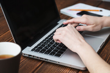 person writing in notebook, studying in front of computer